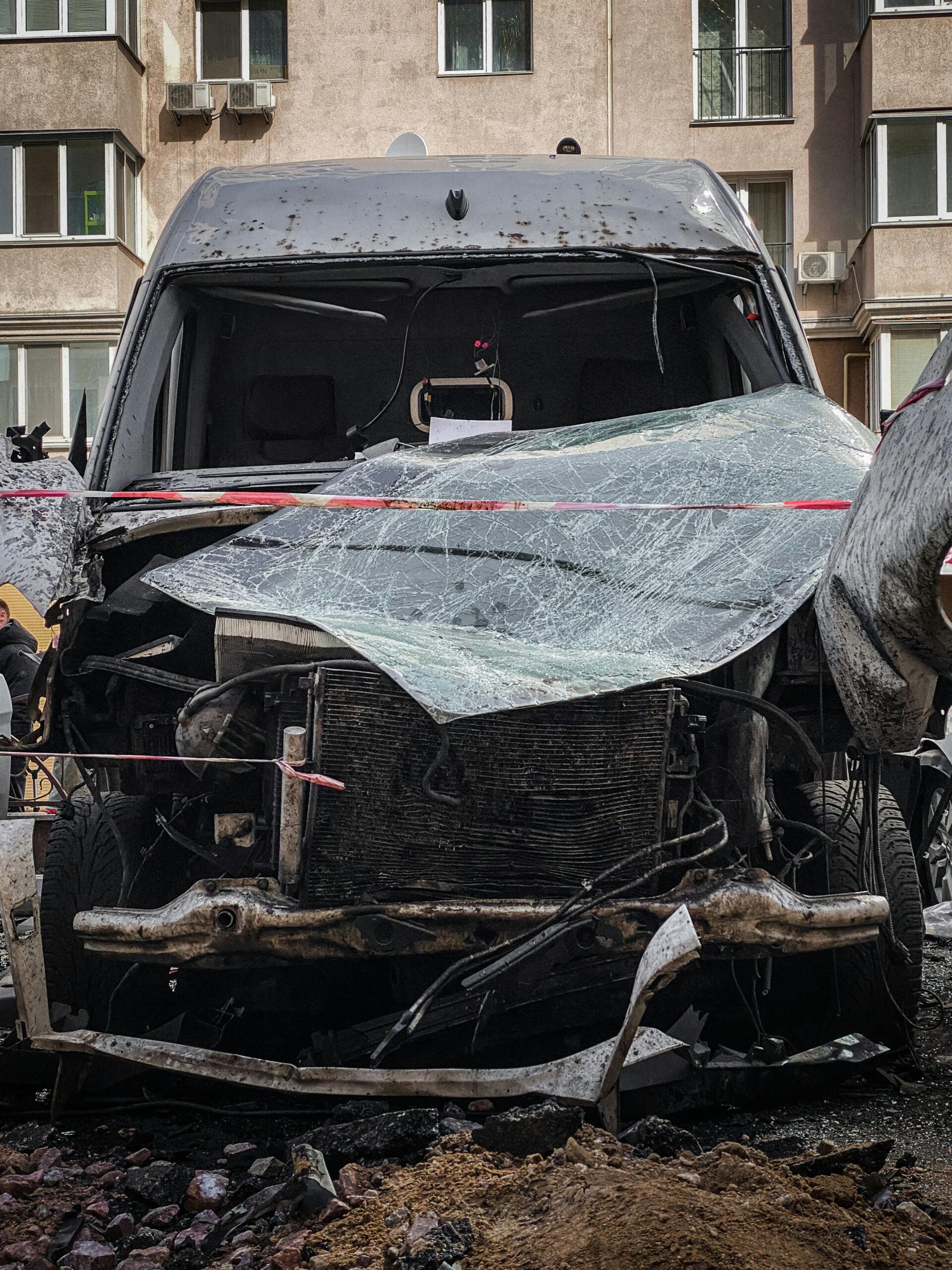 Front view of a wrecked car in a residential Kiev neighborhood, showcasing urban impact.