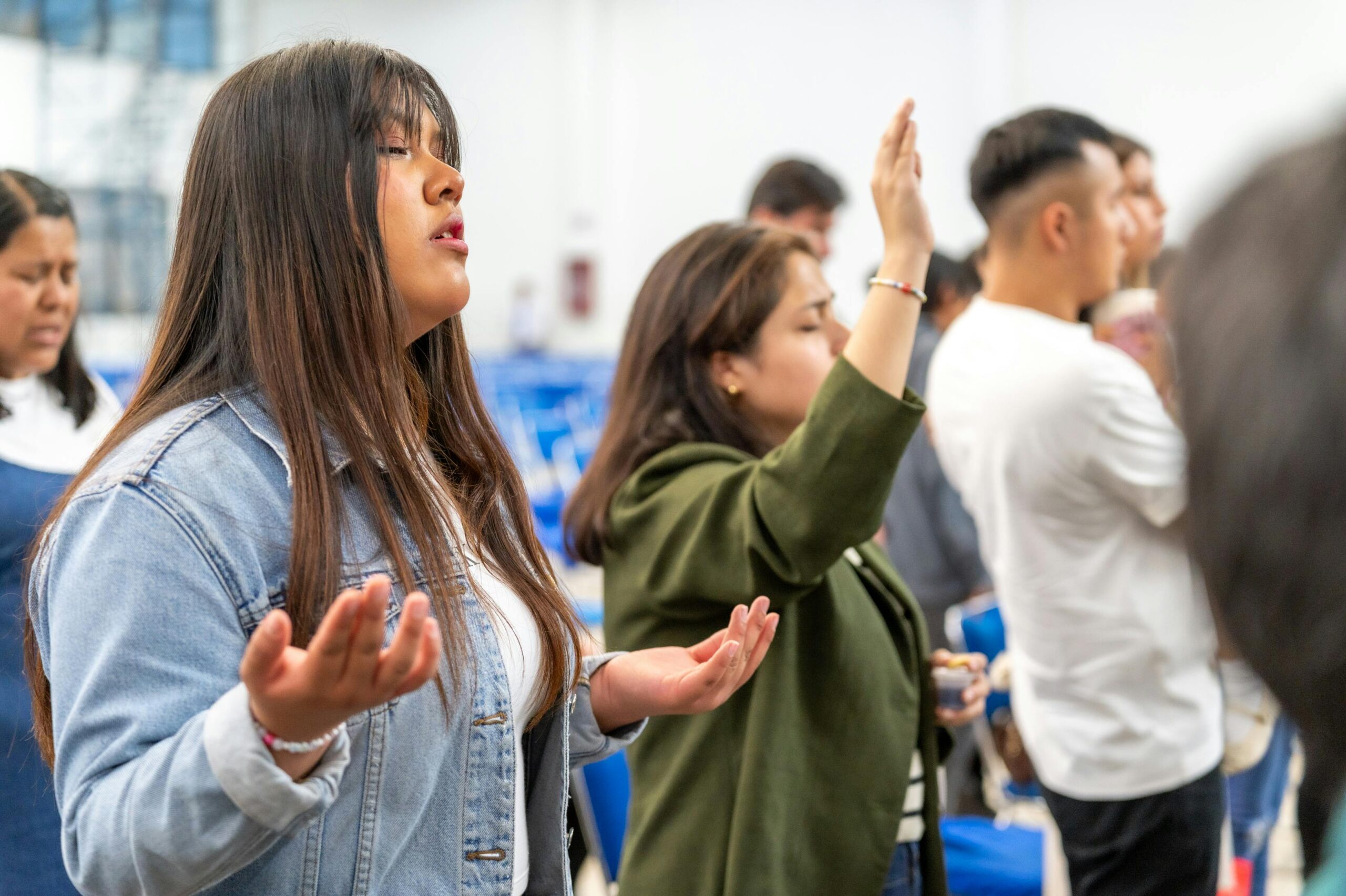 A group of people engaged in worship at an indoor gathering in Ciudad de México.