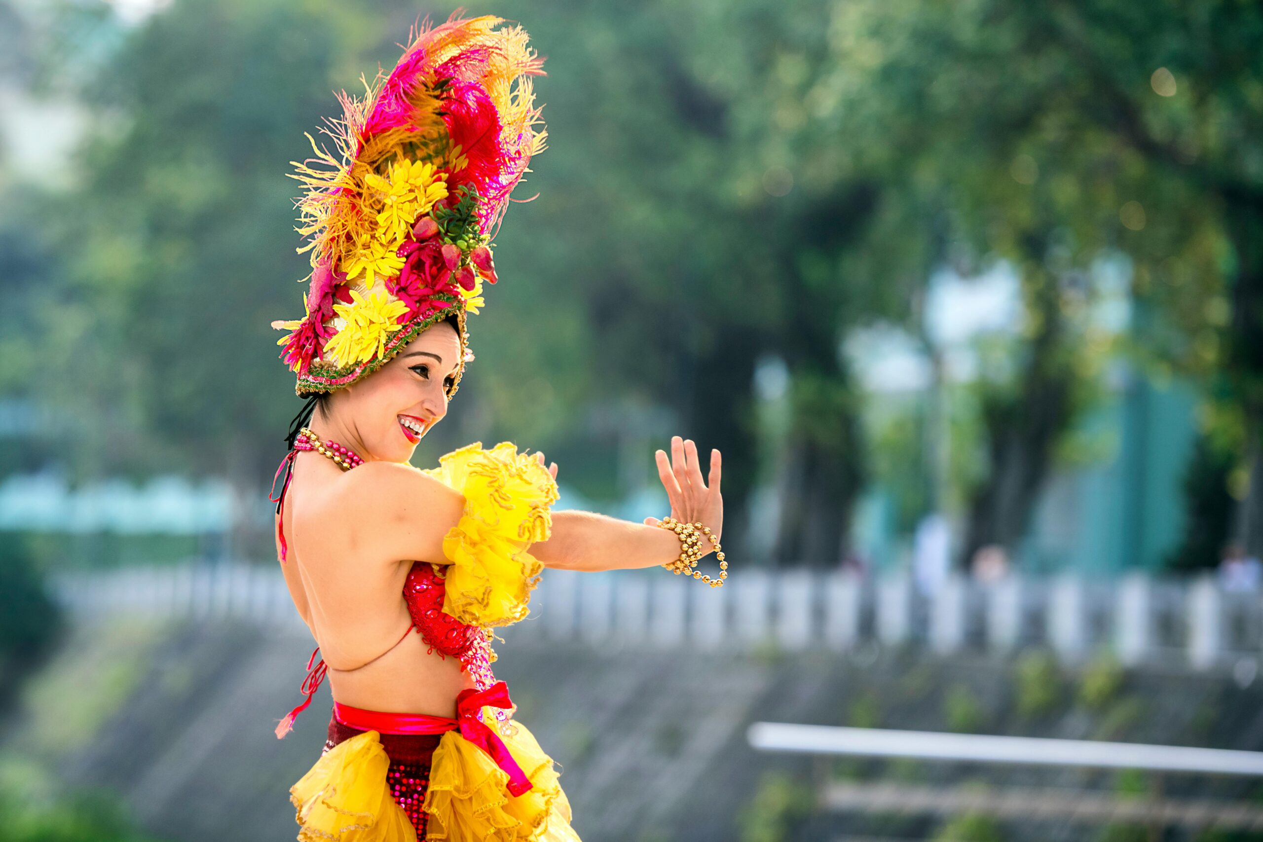 Cheerful woman in vibrant attire dancing at a lively outdoor festival.