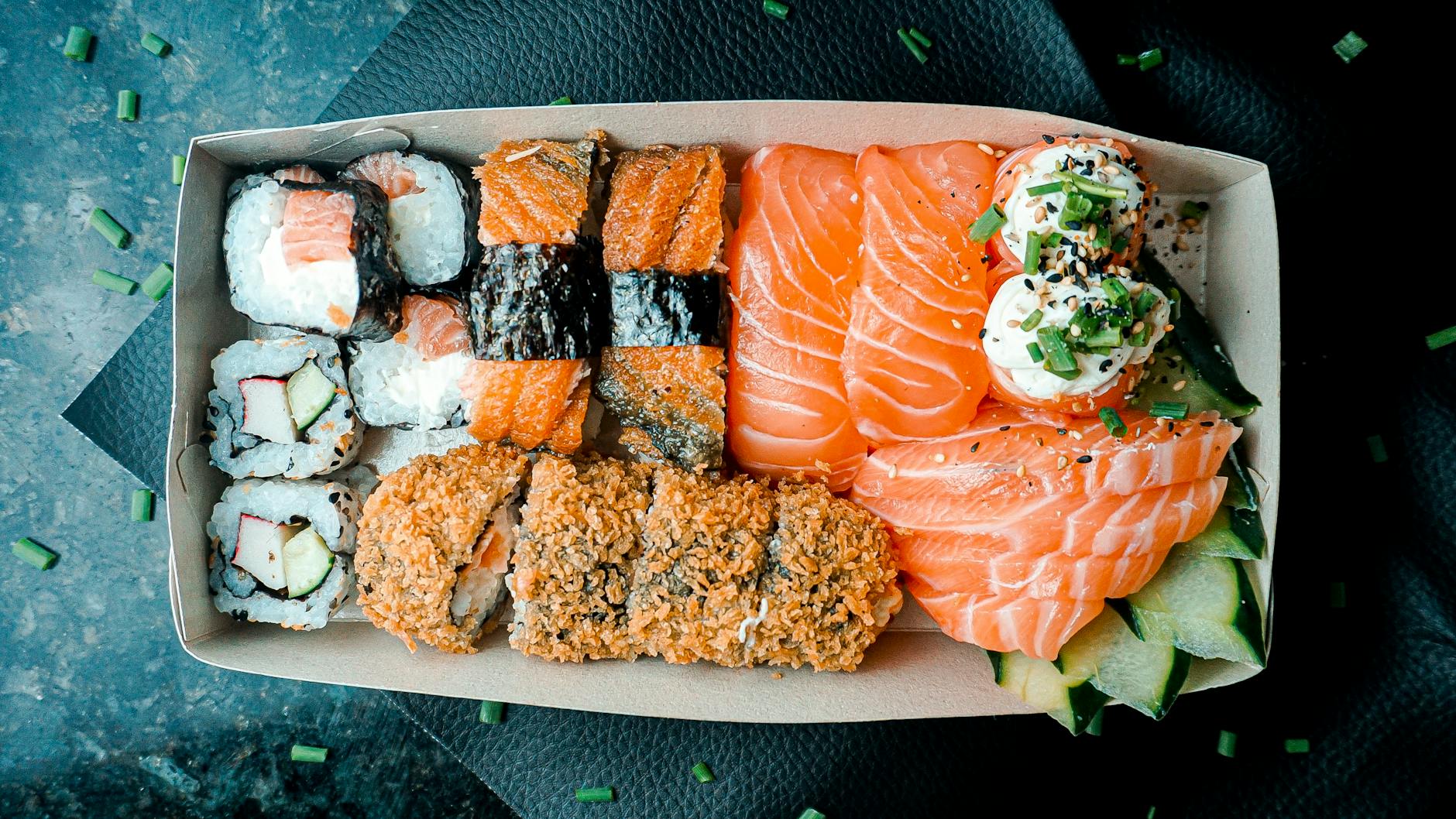 A vibrant box of sushi and sashimi featuring salmon and tuna, perfect for food lovers.