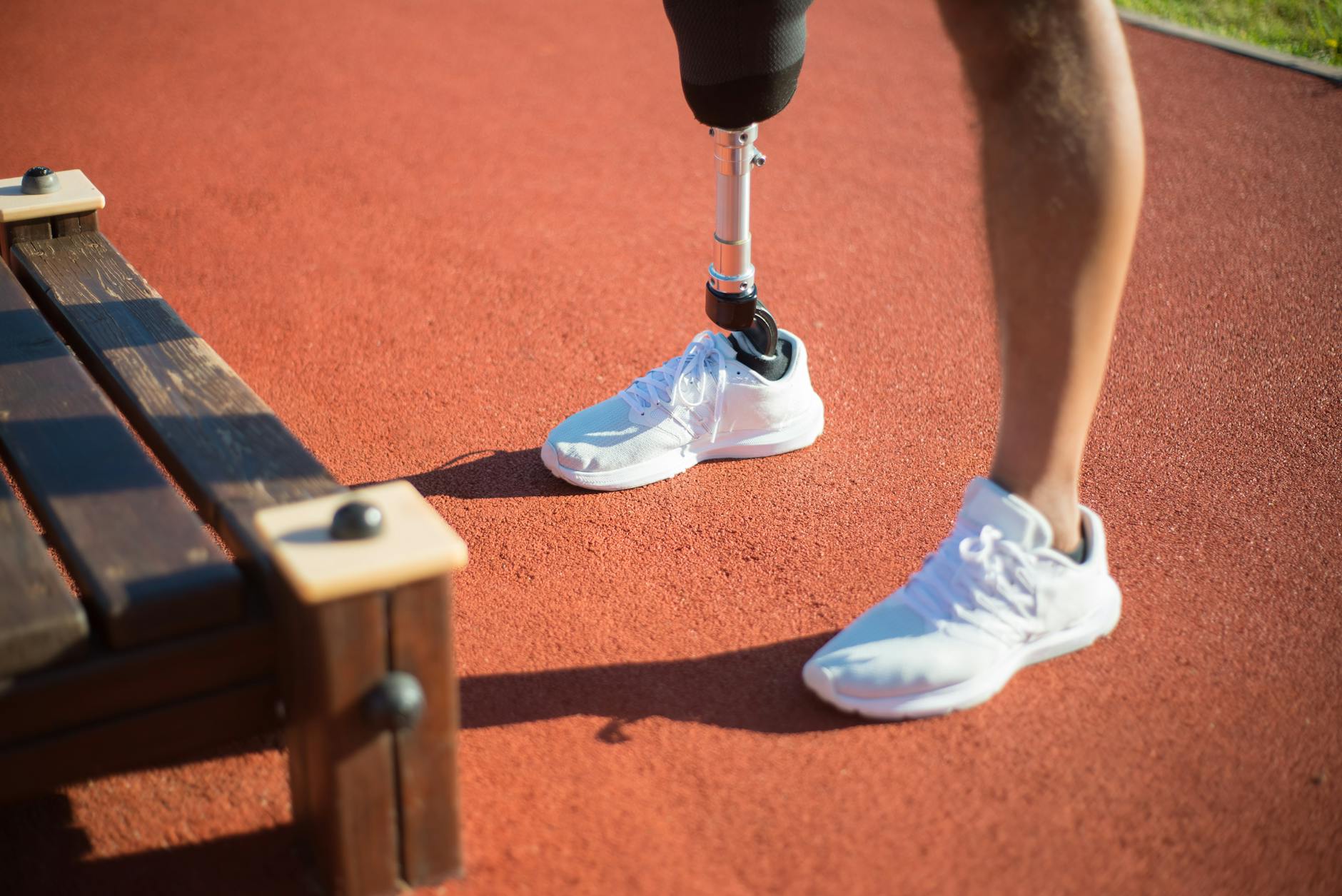 A determined athlete with a prosthetic leg standing on an outdoor track, showcasing resilience and fitness.