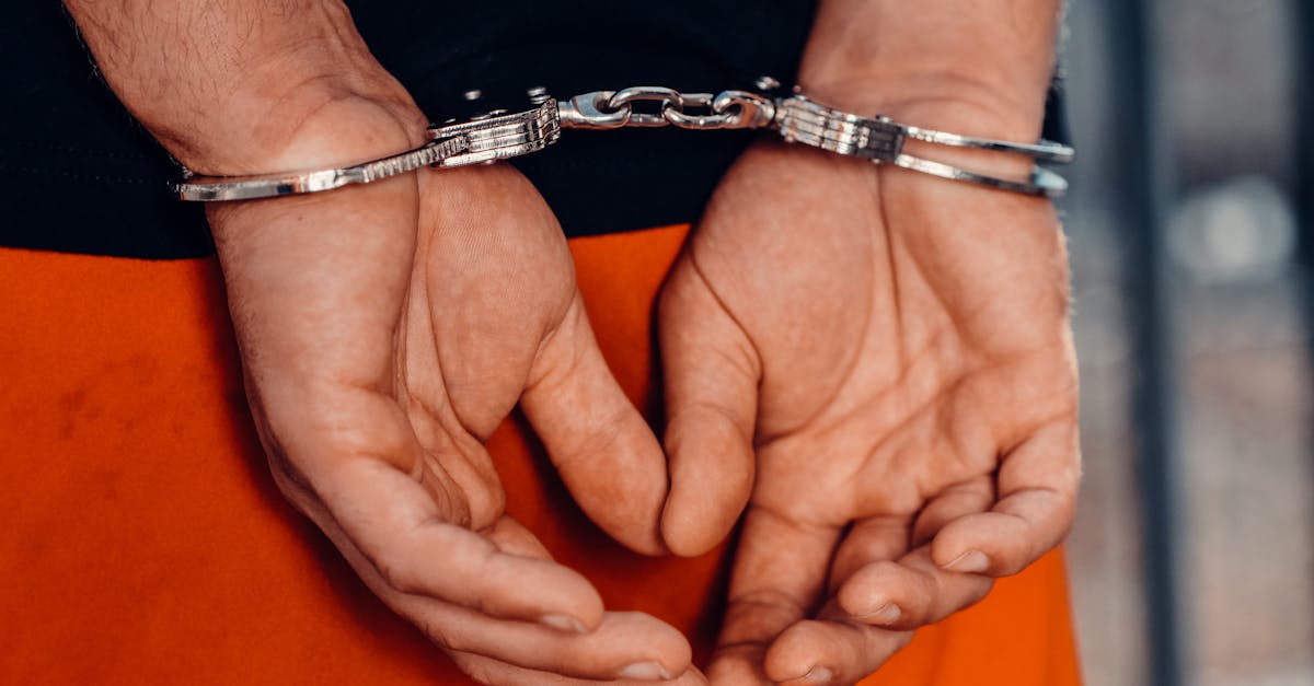 Rear view of handcuffed person in orange uniform, highlighting law enforcement and justice themes.
